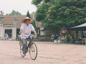 Elderly man rides a bicycle in a traditional Hà Nội street market, Vietnam.