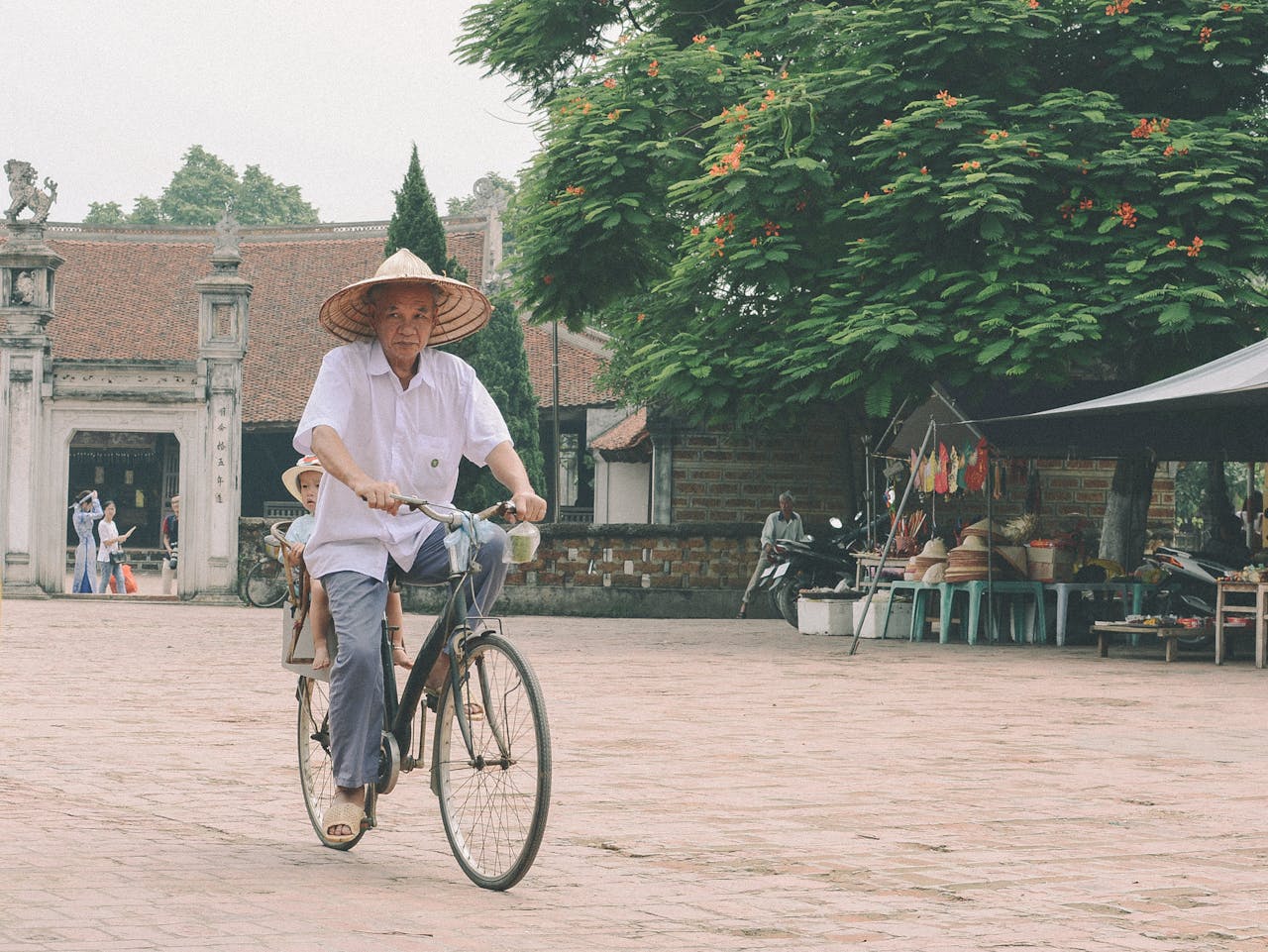 services-01 Elderly man rides a bicycle in a traditional Hà Nội street market, Vietnam.
